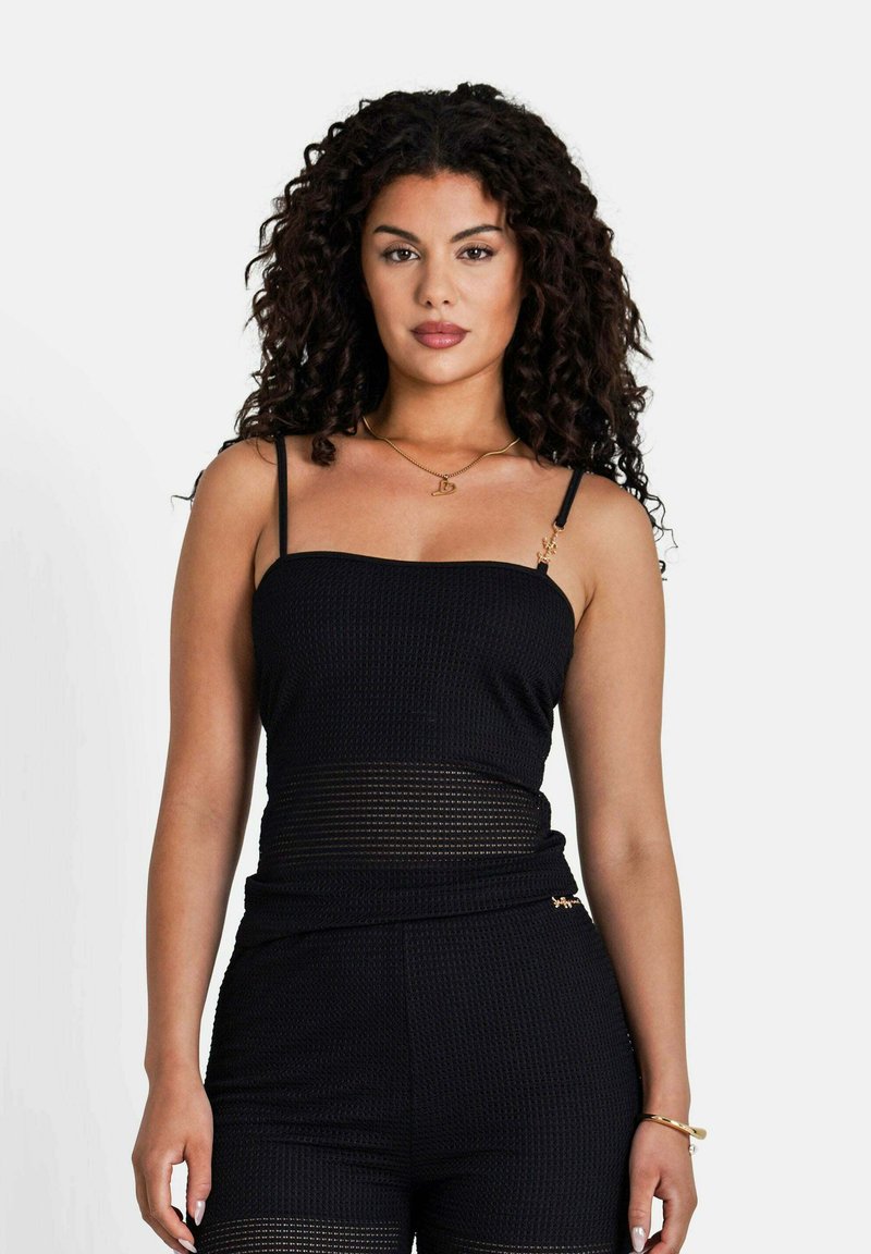 Svart figurnära topp med tunna band, texturerad tyg och genomskinliga paneler vid midjan. Guld detaljer på banden ger kontrast.