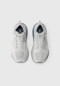 Light gray athletic shoes with mesh upper, rounded toe, and blue outsole. Features prominent laces and padded collar for comfort.