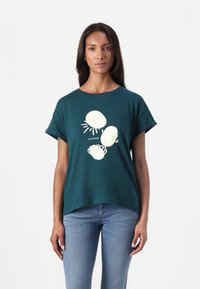 Teal bomull T-skjorte med korte rullet ermer og en avslappet passform, med et lys gult skjell- og solmotiv på forsiden.