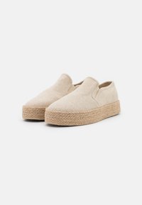 Scarpe slip-on beige realizzate in tessuto testurizzato, con suola in juta intrecciata, dalla forma piatta e arrotondata e design minimalista.