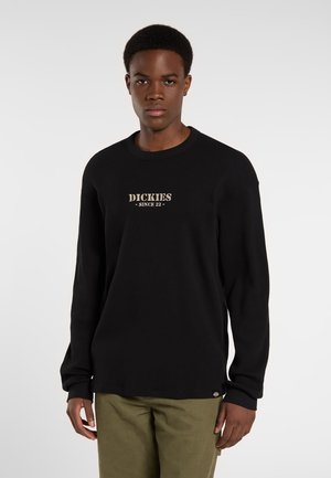 Black long-sleeve ribbed sweater with a crew neck, featuring a golden "DICKIES" logo and small logo tag on the hem.