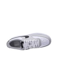 White and gray sneaker with a perforated toe, black swoosh logo, lace-up design, and textured side panels. Flat sole with minimal tread.