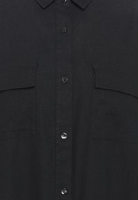 Camicia nera con bottoni, realizzata in tessuto testurizzato, con due tasche frontali, colletto classico e bottoni scuri.