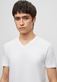 White cotton t-shirt with short sleeves and a V-neckline. The fabric appears soft and smooth, featuring a simple, minimalist design.