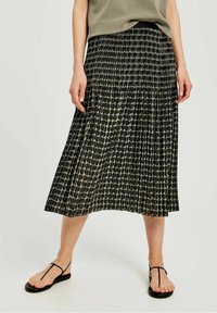 Gonna midi plissettata con un motivo astratto testurizzato in bianco e nero, caratterizzata da una vita elastica e un design fluido. Abbinata a sandali piatti.