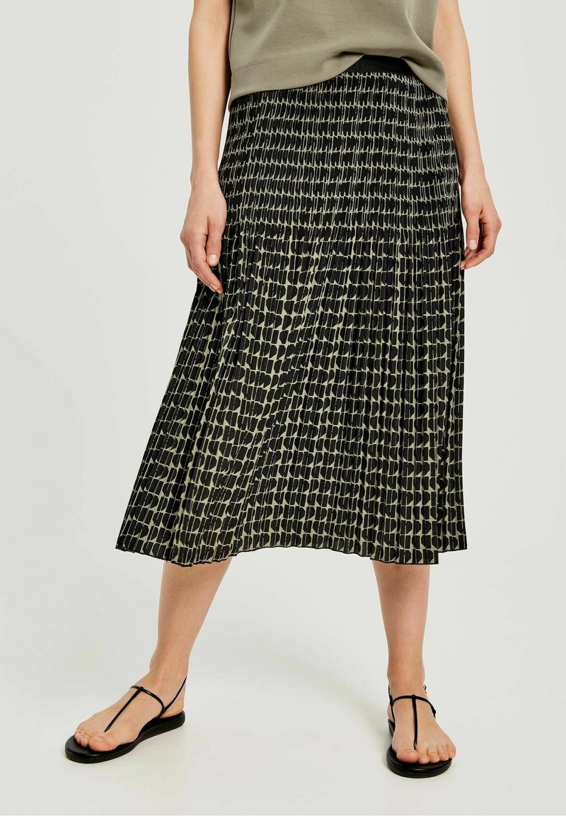 Gonna midi plissettata con un motivo astratto testurizzato in bianco e nero, caratterizzata da una vita elastica e un design fluido. Abbinata a sandali piatti.
