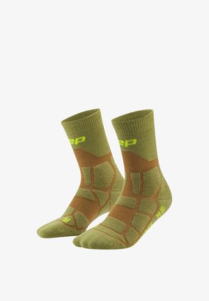 Pair of green and brown cushioned crew socks with geometric patterns and yellow brand logo near the top and toes.