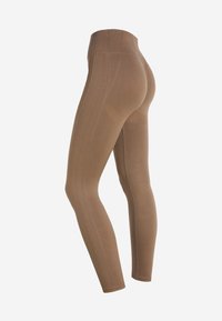 Leggings marroni realizzati in un tessuto elasticizzato. Presentano una vita alta, un design aderente e cuciture visibili lungo i lati.