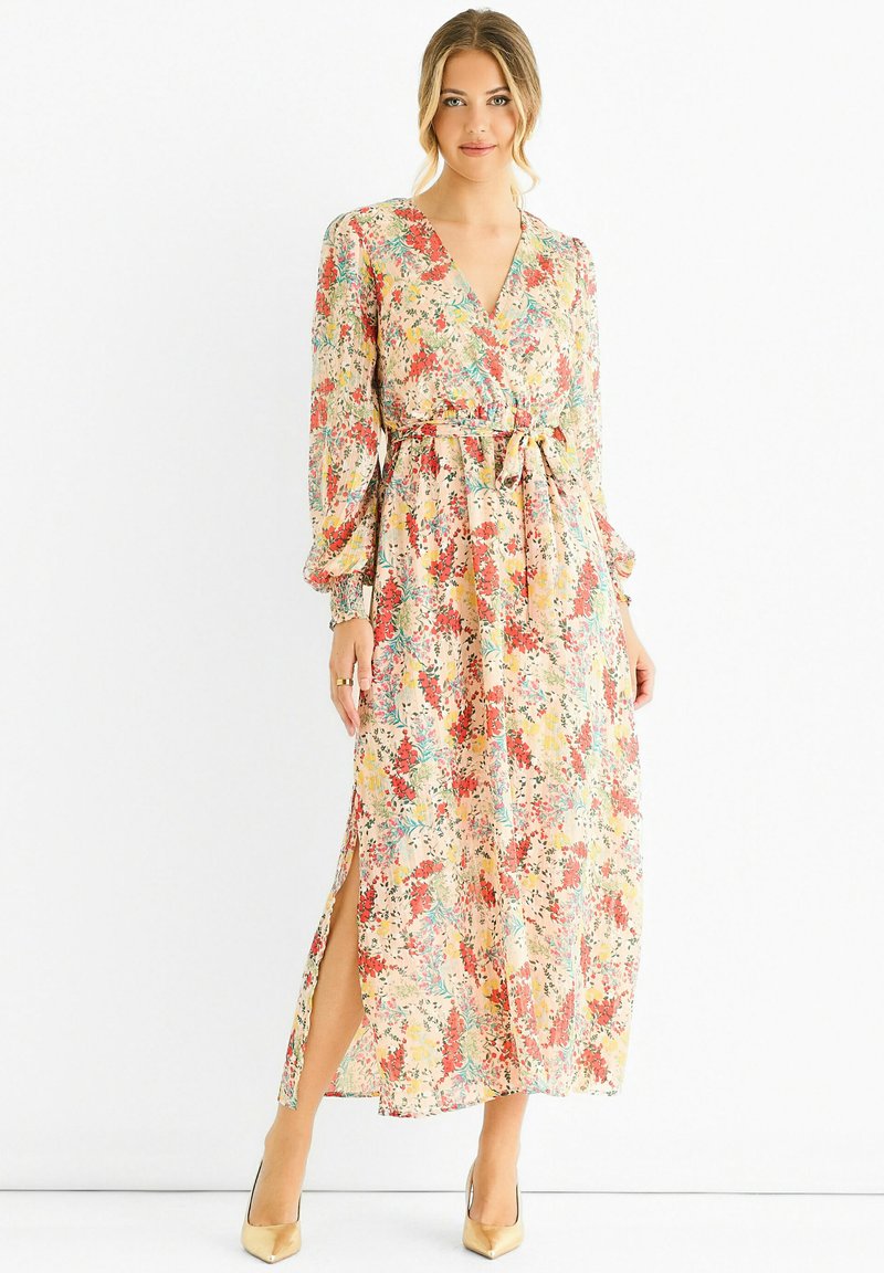 Floral maxi dress with long puff sleeves, v-neckline, cinched waist, and side slits; features muted pastel colors and a textured fabric.