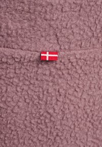 Gestructureerde roze fleece stof met een zichtbaar label van de rode en witte Deense vlag, die een zachte en pluizige uitstraling toont.