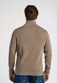 Beige Rippstrickpullover mit mock Neckline, langen Ärmeln und lässiger Passform. Verfügt über einen seitlichen Schlitz am Saum und ein strukturiertes Material.