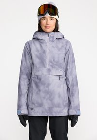 Chaqueta de esquí de color púrpura claro con un diseño estampado, capucha ajustable, cremallera frontal y puños elásticos. Se lleva con gafas de esquí y guantes.