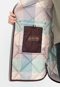 Gefütterte Jacke mit einem mehrfarbigen Karomuster in Pastellfarben. Enthält eine braune Tasche mit Pflege-Symbolen für wasserabweisende, wasserdichte und federnfreie Eigenschaften.