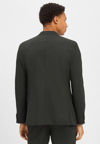 Marynarka w ciemnozielonym kolorze o eleganckim kroju, z pojedynczym rozcięciem z tyłu i dopasowanym fasonem. Tekstura wydaje się gładka i profesjonalna.