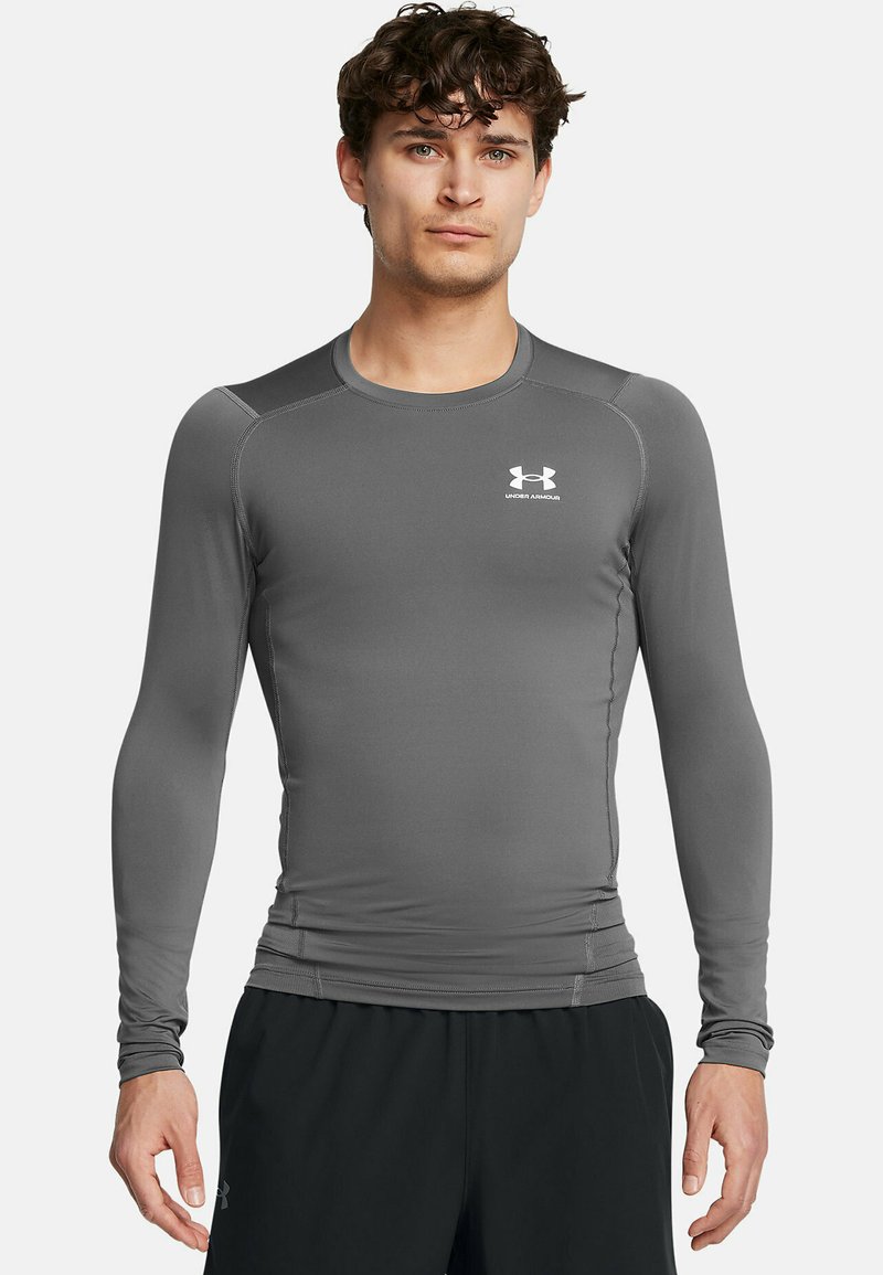 Graues langärmliges Sportshirt mit rundem Ausschnitt, tailliertem Schnitt und dem weißen Under Armour-Logo auf der Brust. Glatte Textur.
