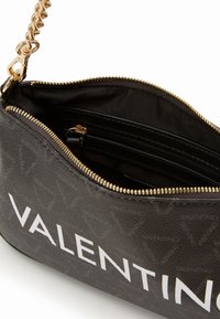Borsa a tracolla nera con texture, caratterizzata da una cerniera dorata, una tracolla a catena e un logo bianco. L'interno include una tasca con zip e scomparti per carte.
