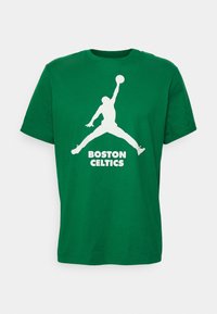Vihreä puuvillainen t-paita lyhyillä hihoilla, jossa on valkoinen Jordan-siluetti ja "BOSTON CELTICS" -teksti tulostettuna alapuolelle.