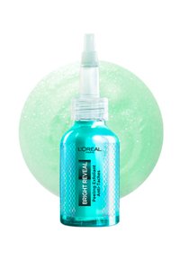 Exfoliant peeling Bright Reveal dans une bouteille turquoise transparente avec un bec verseur. L'arrière-plan présente un cercle vert doux et scintillant.