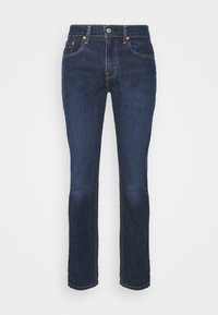 Jeans de ganga azul escuro com corte reto, apresentando costuras em contraste, cinco bolsos e fecho frontal com botão.