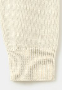 Primo piano di tessuto lavorato a maglia color crema che mostra il dettaglio del polsino a coste con un motivo di punti stretti e uniformi.