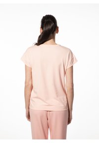 Lichtroze t-shirt met korte mouwen van zachte stof, met een casual ronde hals en een ontspannen pasvorm, gedragen met bijpassende roze broek.