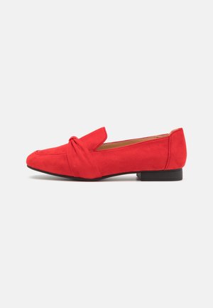 Mocassins en daim rouge avec un détail noué à l'avant. Dessus arrondi et petit talon noir. Texture lisse avec une couleur vibrante.