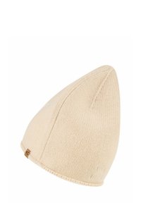 Knit beanie in light beige, featuring a pointed top. The fabric has a textured appearance with a small branded leather tag on the side.