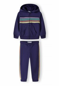 Tummansininen vetoketjullinen huppari, jossa on moniväriset raidat rinnassa, ja yhteensopivat tummansiniset housut, joissa on raidoitettuja sivuakkentteja. Puuvillasekoituskangas.