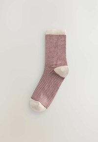 Pruhovaná ponožka v burgundské a krémové barvě, se žebrovaným lemem, vyztuženou špičkou a jemnou strukturou. Design se skládá z střídajících se úzkých pruhů.
