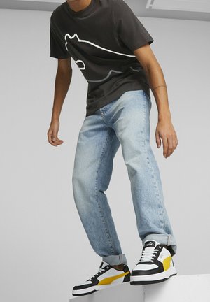 Black short-sleeve t-shirt with white outline graphic, light blue straight-leg jeans, and black, white, and yellow sneakers. Smooth textures.