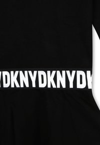 Czarny strój o dopasowanym kroju z poziomym białym paskiem, na którym powtarzany jest tekst pogrubioną czcionką. Miękka faktura tkaniny.