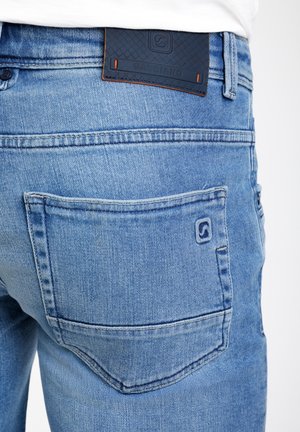 Heledad sinine teksarihm, millel on nähtav tagatasku ja tekstuuriga tume sinine nahkpood, millel on sisse pressitud "GABBIANO".