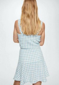 Vestido de tela a cuadros azul y blanco con falda acampanada, diseño sin mangas y superficie texturada. Silueta clásica con corsé ajustado.