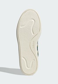 Gumeni potplat cipela s teksturiranom površinom, s valovitom šablonom i utisnutim logom "adidas" u bijeloj boji. Pretežno ravni dizajn.