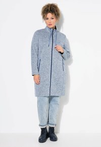 Blå zip-up jacka med hög krage, två sidofickor och kontrasterande marinblå detaljer. Mjuk, texturerad tyg med en avslappnad passform.