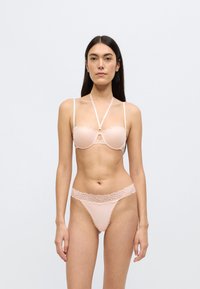 Σετ εσωρούχων ανοιχτό ροζ με δαντέλα, που περιλαμβάνει σουτιέν χωρίς τιράντες με γεωμετρικό σχέδιο και τανγκό με κυματιστά τελειώματα.