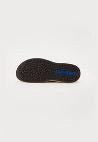 Sole in gomma nera con un distintivo motivo ondulato. La parola "BIRKENSTOCK" è stamparata in blu vicino al tallone. Superficie liscia.