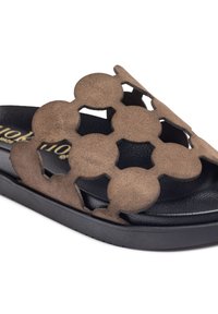Brown suede slide sandal with a cut-out circular design, black textured footbed, and a black rubber sole. Soft and flexible texture.