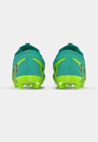 Green athletic shoes with a textured upper, featuring bright yellow accents and a low heel. Cleated sole for traction on grass surfaces.