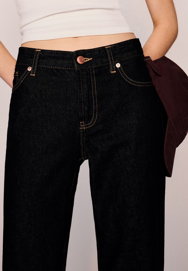 Mörka denimjeans med hög midja, gul sömnad och fem fickor. Med kopparknapp och kontrasterande beslag.