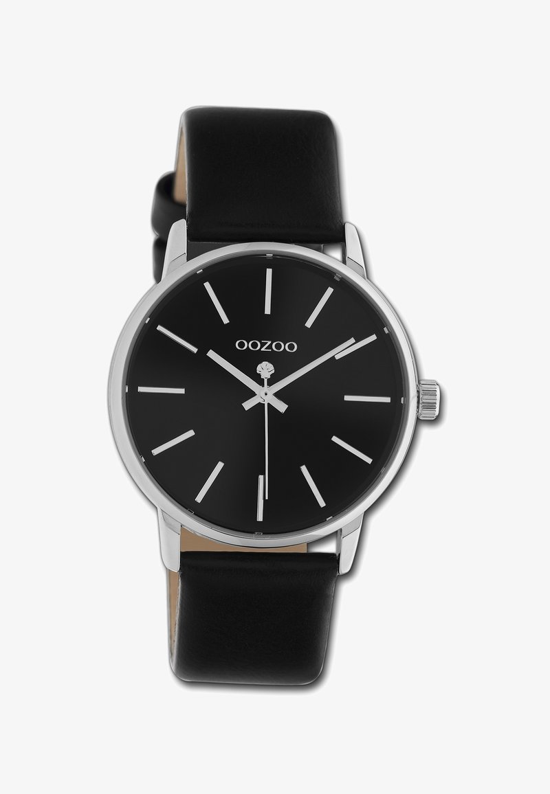 Montre noire avec index argentés, design minimaliste, boîtier rond et bracelet en cuir noir. Présente un cadran simple et une couronne.