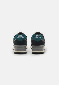 Modré a černé retro tenisky z nubuku s šedou podrážkou a bílým logem "new balance" na patě. Obsahují polstrovaný límec a texturované vzory.