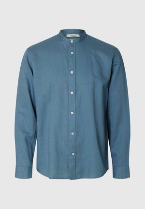 Pitkähihainen sininen nappipaita, jossa on mandariinikaulus, valkoiset napit edessä ja napilliset hihansuut.