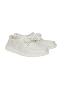 Chaussures légères beiges en tissu texturé, avec un détail noué sur le dessus et une semelle en caoutchouc blanche.