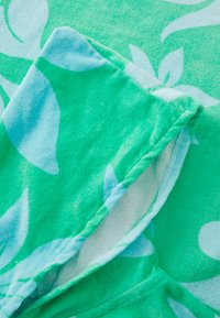Lichtgroene hoodie van een zachte, gestructureerde stof, met een wit loofpatroon. De capuchon is iets omgevouwen, waardoor de details van de binnenvoering zichtbaar zijn.