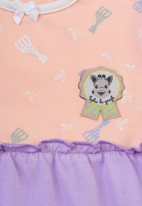 Abito di cotone nei colori pesca e lavanda. Presenta piccoli motivi di utensili e un distintivo con una giraffa sorridente. Orlo arruffato in lavanda.