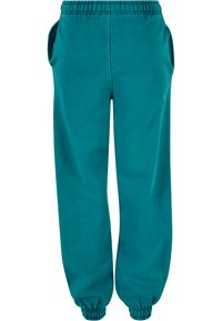 Tyrkise joggebukser laget av myk stoff. Har elastisk midje, sidelommer og elastiske mansjetter ved anklene.
