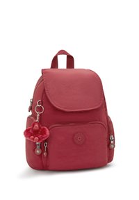 Mochila roja de nailon con cierre de solapa y bolsillo frontal. Cuenta con un llavero de mono y un logo en la parte frontal. Correas ajustables y un asa superior.
