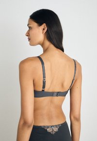 Gray ribbed bra with adjustable straps and hook closure, featuring delicate embroidery detailing on the band and soft texture.