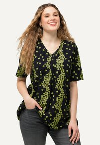 Černý top s v-výstřihem a krátkými rukávy, pokrytý zeleným květinovým vzorem. Materiál je měkký, s uvolněným střihem a bočními kapsami.